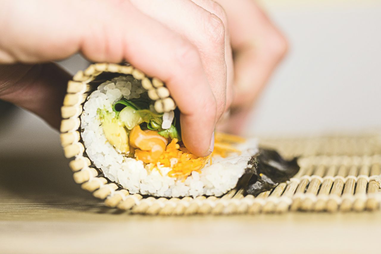 persona che arrotola sushi